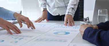 Ofis masasında çizelgeleri, grafikleri ve finansal veri tablolarını inceleyen bir grup profesyonel. Takım çalışması, strateji, iş planlaması ve kurumsal karar verme kavramı