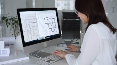 İnşaat planları üzerinde çalışan kadın mimar kaba yazılım kullanıyor, ofisinde yeni bir emlak tasarımı geliştiriyor. İş ve mimari kavramı