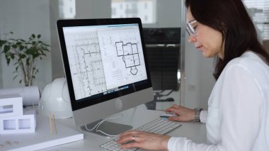İnşaat planları üzerinde çalışan kadın mimar kaba yazılım kullanıyor, ofisinde yeni bir emlak tasarımı geliştiriyor. İş ve mimari kavramı