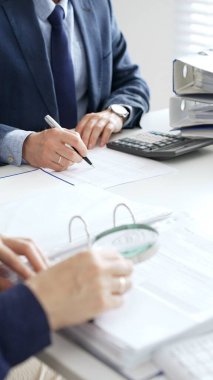 Ekonomik belgeleri analiz eden, hesap makineleri ve dizüstü bilgisayarlar kullanan iş adamları modern ofiste proje üzerinde birlikte çalışıyorlar. Denetim ve vergi kavramı.