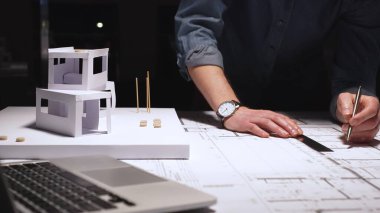 Mimari mimari planlama ve tasarımın temel unsurlarını temsil eden kağıt modeller üzerinde çalışmak ve dizüstü bilgisayar kullanmak için ayrıntılı çizgiler çizer