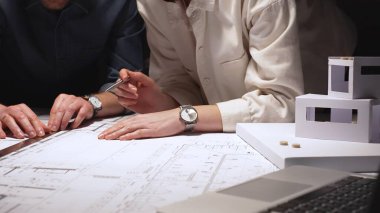 Mimarlık uzmanları teknik planları analiz ediyor ve yeni bir şehir gelişimi tasarlamak için taslak araçları kullanıyorlar. Yakınlardaki ölçekli bir modelle inşaat planlama ve mühendislik tasarımına odaklanıyor.