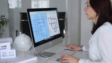 İnşaat planları üzerinde çalışan kadın mimar kaba yazılım kullanıyor, ofisinde yeni bir emlak tasarımı geliştiriyor. İş ve mimari kavramı