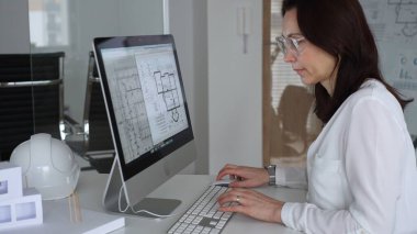 İnşaat planları üzerinde çalışan kadın mimar kaba yazılım kullanıyor, ofisinde yeni bir emlak tasarımı geliştiriyor. İş ve mimari kavramı