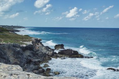 Meksika, Cancun açıklarındaki küçük bir ada olan Isla Mujeres 'deki kayalıklara çarpan güçlü dalgalar ve dalgalı deniz suyunun dramatik bir görüntüsü.