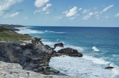 Meksika, Cancun açıklarındaki küçük bir ada olan Isla Mujeres 'deki kayalıklara çarpan güçlü dalgalar ve dalgalı deniz suyunun dramatik bir görüntüsü.