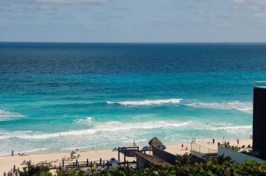 Turkuaz deniz suyu ve Meksika 'nın Cancun kentindeki güzel plajda dinlenen turistlerin büyüleyici manzarası.