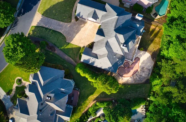 Top down view of beautiful houses, roofs and lush green landscaped yards in an upscale subdivision in suburbs of USA shot during Golden hour during early spring.