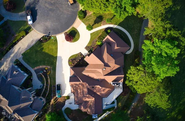 Top down view of beautiful houses, roofs and lush green landscaped yards in an upscale subdivision in suburbs of USA shot during Golden hour during early spring.