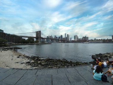 New York, ABD-2 Temmuz 2021: Turistler ve yerel turistler, Brooklyn, New York 'taki Pebble Beach' te Hudson Nehri kıyılarından Manhattan Skyline ve Brooklyn Köprüsü manzarasının keyfini çıkarıyorlar.