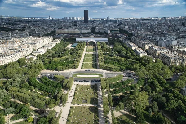 A panoramic aerial view of Paris skyline including river Seine lined with boats, a golden doom of Palace of invalides and other historical monuments, parks and gardens