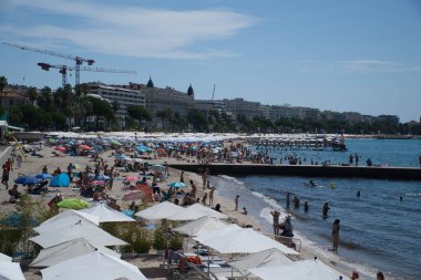 Cannes, Fransa - 3 Ağustos 2021: Fransa 'nın Cannes kentindeki ünlü Plage des Rochers plajında güneşli bir günde dinlenen kalabalık.