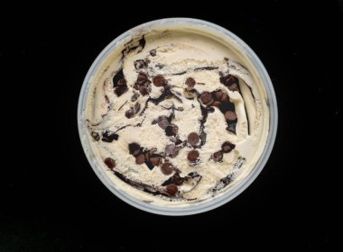 Çikolata çizgilerini, kremsi dokuları ve siyah arkaplanda çekilmiş fotoğrafı gösteren bir kavanoz kremalı dondurma. 