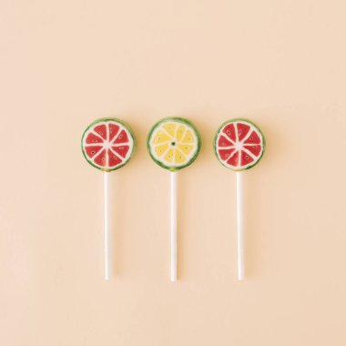 Üç tane meyveli lolipop, karpuz ve krema arkaplanda limon suratlı. Şeker Minimum gıda yaz konsepti