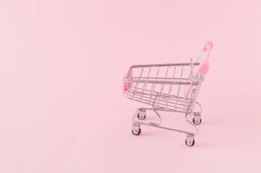 Pembe arka planda büyük bir fotokopi alanı olan boş bir alışveriş arabası. Monokromatik renklerle çevrimiçi alışveriş kavramı