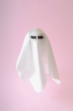 Pembe arka planda kirpikleri olan beyaz bir hayalet. Cadılar Bayramı korkunç geçmişi. En düşük bileşim