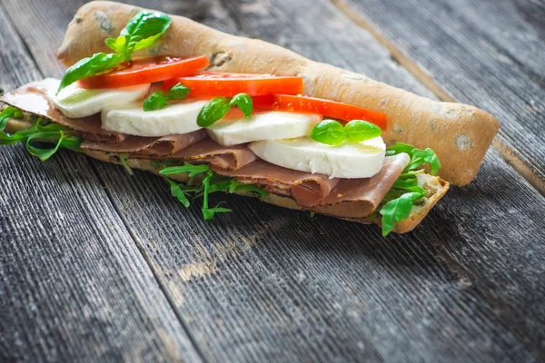 Ahşap arka plan üzerinde Mozzarella peyniri ile sandviç