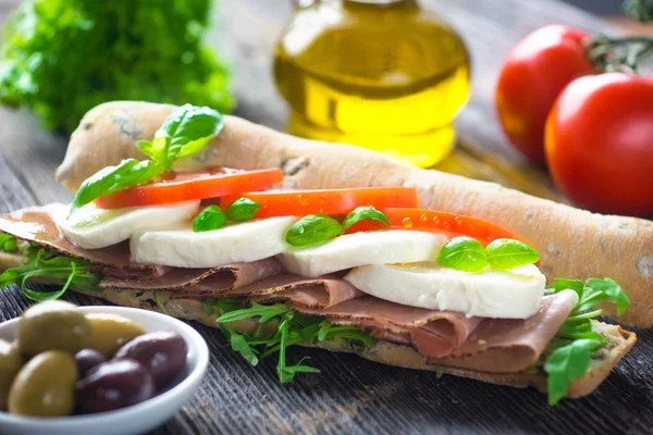 Сэндвич с хрустящим багетом на деревянном фоне — стоковое фото