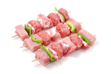 Domuz pastırmalı çiğ domuz şişi, sosis, tatlı biber ve et, beyaz arka planda izole edilmiş.