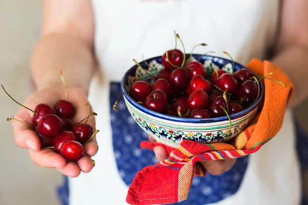 Cherries in ceramic bowl and colorful towel in the hands — Stock Photo, Image