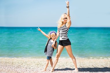 Güzel kadın ve sevimli kızı kumsalda dinlenme