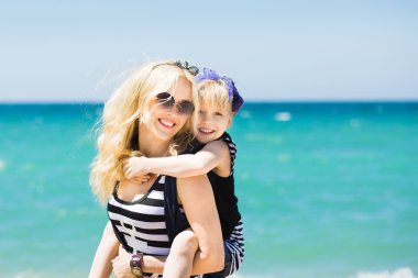 Güzel kadın ve sevimli kızı kumsalda dinlenme