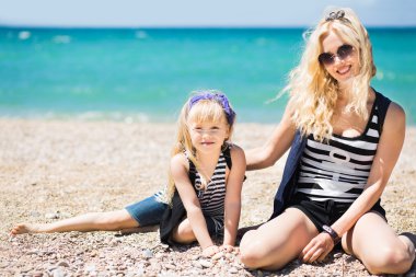 Güzel kadın ve sevimli kızı kumsalda dinlenme