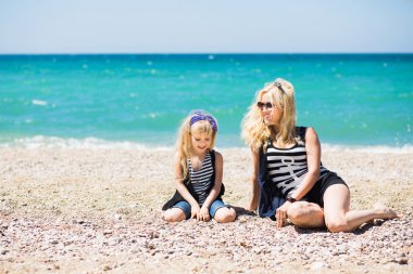 Güzel kadın ve sevimli kızı kumsalda dinlenme