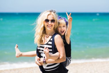 Güzel kadın ve sevimli kızı kumsalda dinlenme