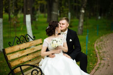 Düğün günü: parkta bankta oturmak güzel gelin ve damat