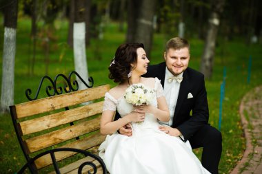 Düğün günü: parkta bankta oturmak güzel gelin ve damat