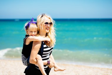 Güzel kadın ve sevimli kızı kumsalda dinlenme 