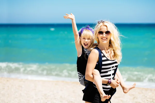 Красивая женщина и ее очаровательная дочь отдыхают на пляже Стоковое Изображение