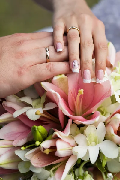 Wedding rings and hands at the wedding bouquet — Stock Photo, Image