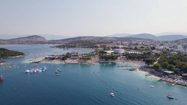 Drone perspective of Ksamil Beach Albania showing sandy beach, turquoise sea, and colorful coastal bars along the shore