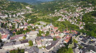 Drone aerial view of Jajce showing the cityscape with a historic church, surrounding buildings, and streets