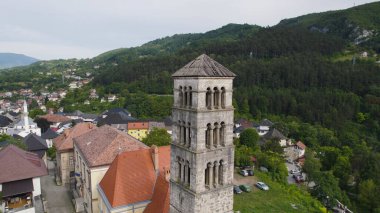 Drone aerial view focusing on the tower of Saint Marys Church in Jajce, showing detailed architecture and surrounding cityscape