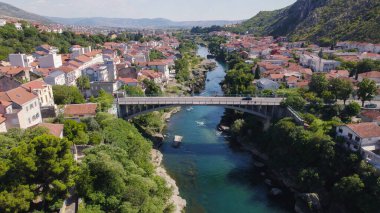Mostar 'daki Neretva Nehri üzerindeki Luccki Most köprüsünü gösteren hava aracı fotoğrafı. Geleneksel binalar nehir kıyılarını kaplıyor..