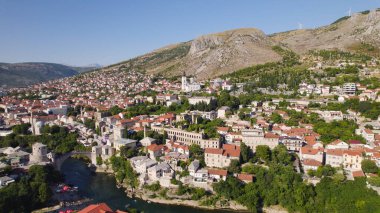 Mostar 'daki Neretva Nehri boyunca uzanan tarihi binalarla Kutsal Üçlü Katedrali' ni gösteren İHA hava fotoğrafı, kentin manzaralı eski kenti ve Balkan manzarasını vurguluyor..