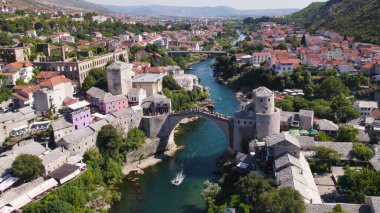 İnsansız hava aracı fotoğrafı, Stari Most köprüsünün canlı renkli evlerle Neretva Nehri 'ni kapladığını gösteriyor. Mostars' ın tarihi kasabasının cazibesini vurguluyor..