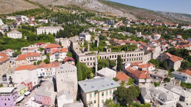İnsansız hava aracı Mostar 'da savaştan zarar görmüş tarihi bir bina gösteriyor. Çevredeki kentlerin tarihi ve esnekliğini vurguluyor..
