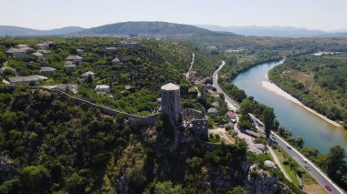 Bosna-Hersek 'in yemyeşil ve geleneksel taş mimarisi ile çevrili Neretva Nehri' nin üzerinde duran Pocitelj Kalesi 'ni gösteren insansız hava aracı fotoğrafı.