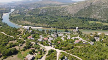 İnsansız hava aracı fotoğrafı, tarihi Pocitelj Bosna-Hersek köyünü taş evler, dar sokaklar ve yemyeşil çevrelerle gösteriyor.