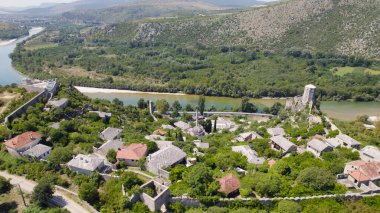 Yeşil tepeler ve ortaçağ mimarisiyle çevrili büyüleyici taş köyü Pocitelj Bosna-Hersek 'in insansız hava aracı fotoğrafı.