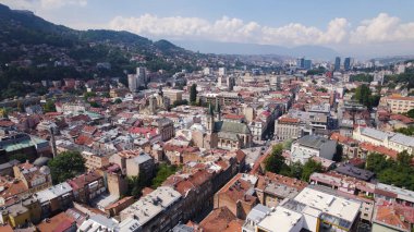 Saraybosna 'daki Kutsal Kalp Katedrali' ni çevreleyen binalar, sokaklar ve kentsel manzaralarla gösteren insansız hava aracı fotoğrafı.