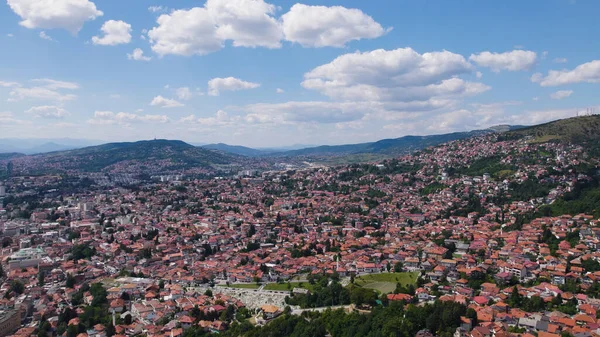 Saraybosna 'da, arka planda dağlar ve kenti çevreleyen yemyeşil yemyeşil yemyeşil evleri gösteren insansız hava aracı fotoğrafı..