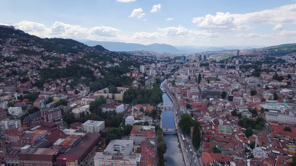 Nehir boyunca Saraybosna 'nın köprüleri, kentsel binalar ve Bosna-Hersek' teki çevre tepeler de dahil olmak üzere kentini gösteren insansız hava aracı fotoğrafı.