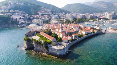 Karadağ 'ın Budva Eski Kenti' nin temiz turkuaz sularla çevrili insansız hava aracı fotoğrafı. Tarihi binaları ve Adriyatik kıyılarının cazibesini vurgulayan manzaralı bir Akdeniz manzarası.