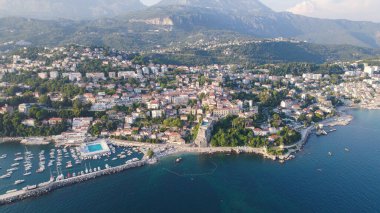 Herceg Novi 'nin rıhtımlarını tekneler ve kıyı binalarıyla gösteren insansız hava aracı fotoğrafı..
