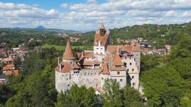 Transilvanya 'daki sık ormanın üzerine tünemiş Bran Kalesi' nin insansız hava aracı görüntüsü.